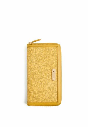 Portafoglio giallo testurizzato con zip lungo tutto il perimetro, angoli arrotondati e piccolo dettaglio con piastra metallica dorata sulla parte anteriore.