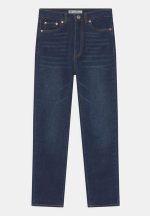 Proste, ciemnoniebieskie dżinsy z pięcioma kieszeniami, miedzianymi nitami i kontrastującymi szwami, ułożone na płasko na białym tle.