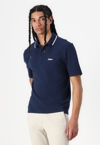 Mornarska polo majica iz gladkega materiala, z belim ovratnikom in izvezenim logotipom na prsih; kratki rokavi in sproščen kroj.