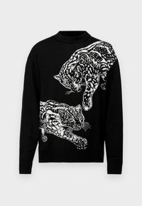 Pullover di maglia nera con un design di leopardi bianchi in movimento. Il collo è rotondo, con polsini e orlo a coste.