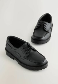 Chaussures en cuir noir avec une texture lisse, bout rond et couture contrastante. Elles sont dotées de lacets et d'une semelle épaisse en caoutchouc noir.