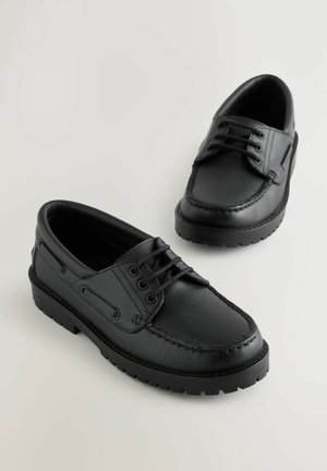 Zwarte leren schoenen met een gladde textuur, ronde neus en contrasterende stiksels. Voorzien van veters en een dikke zwarte rubberen zool.