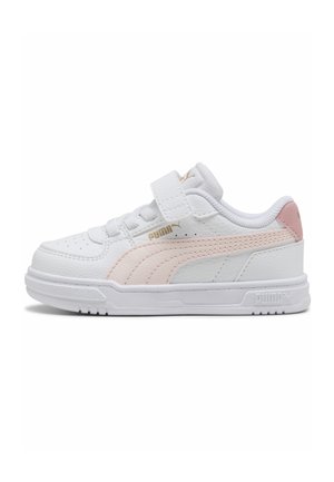 Zapatilla baja de Puma en blanco y rosa con tira de velcro, puntera perforada y suela de goma, mostrada desde el lado exterior.