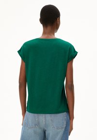 Haut vert à manches courtes avec manches retroussées, présentant un col rond et une coupe décontractée. Le matériau a une texture lisse.