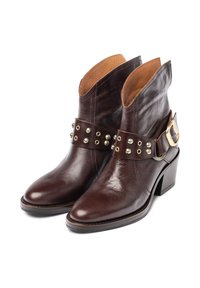 Botas de cuero marrón hasta el tobillo con punta afilada, un tacón grueso y una correa decorativa con tachuelas metálicas y un detalle de hebilla.
