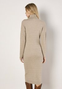 Abito a maglia beige a coste con colletto alto e maniche lunghe, silhouette attillata, lunghezza metà polpaccio, con un motivo testurizzato.