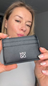 Μαύρος δερμάτινος θήκη καρτών με υφασμένο φινίρισμα, τέσσερις θήκες και ανάγλυφο λογότυπο "HUGO" στο μπροστινό μέρος. Κλείσιμο με φερμουάρ στην κορυφή.