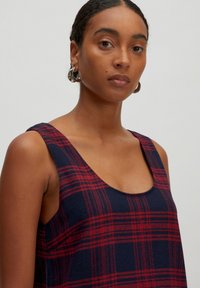 Ärmelloses Kleid aus navy- und rotkariertem, strukturiertem Stoff mit Rundhalsausschnitt und breiten Schulterträgern. Verfügt über ein lässiges Schnittdesign.