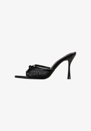 Mule noire à talons hauts ouverte à l'avant, avec tige en mesh et détail de nœud décoratif sur fond blanc.