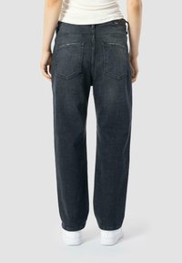 Jean en denim lavé foncé avec une coupe décontractée, jambe droite et deux poches arrière. Présente des coutures discrètes et une texture lisse.