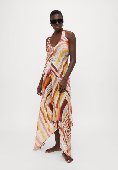 Sundress med halterneck-design, tillverkad av lättviktsmaterial med ett geometriskt mönster i varma toner av orange, rosa och beige.
