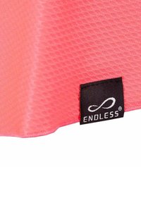 Esquina de una tela rosa texturizada con una etiqueta negra que muestra un símbolo de infinito en blanco y la palabra "ENDLESS" en letras mayúsculas.