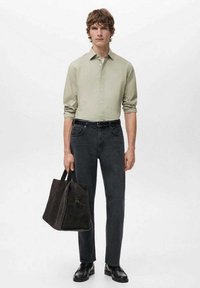 Camisa de manga larga verde claro, jeans oscuros, zapatos negros y un bolso de mano oscuro con asas. Diseño sencillo, ajuste entallado y colores sólidos.