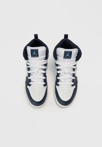 Aukštakulniai sportbačiai su baltu odiniu viršumi, tamsiai mėlynais akcentais ir perforuota nosimi. Turi baltas raištelius ir Jumpman logotipą ant liežuvėlio.