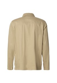 Chemise beige à manches longues en coton. Elle présente un col, une texture unie et une coupe légèrement ample avec un ourlet droit.