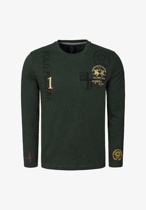 Długorękawowa, ciemnozielona bawełniana koszula z haftowanymi wzorami i tekstem w kolorze złotym i bordowym. Charakterystyczne godło i graficzne akcenty zostały zastosowane.