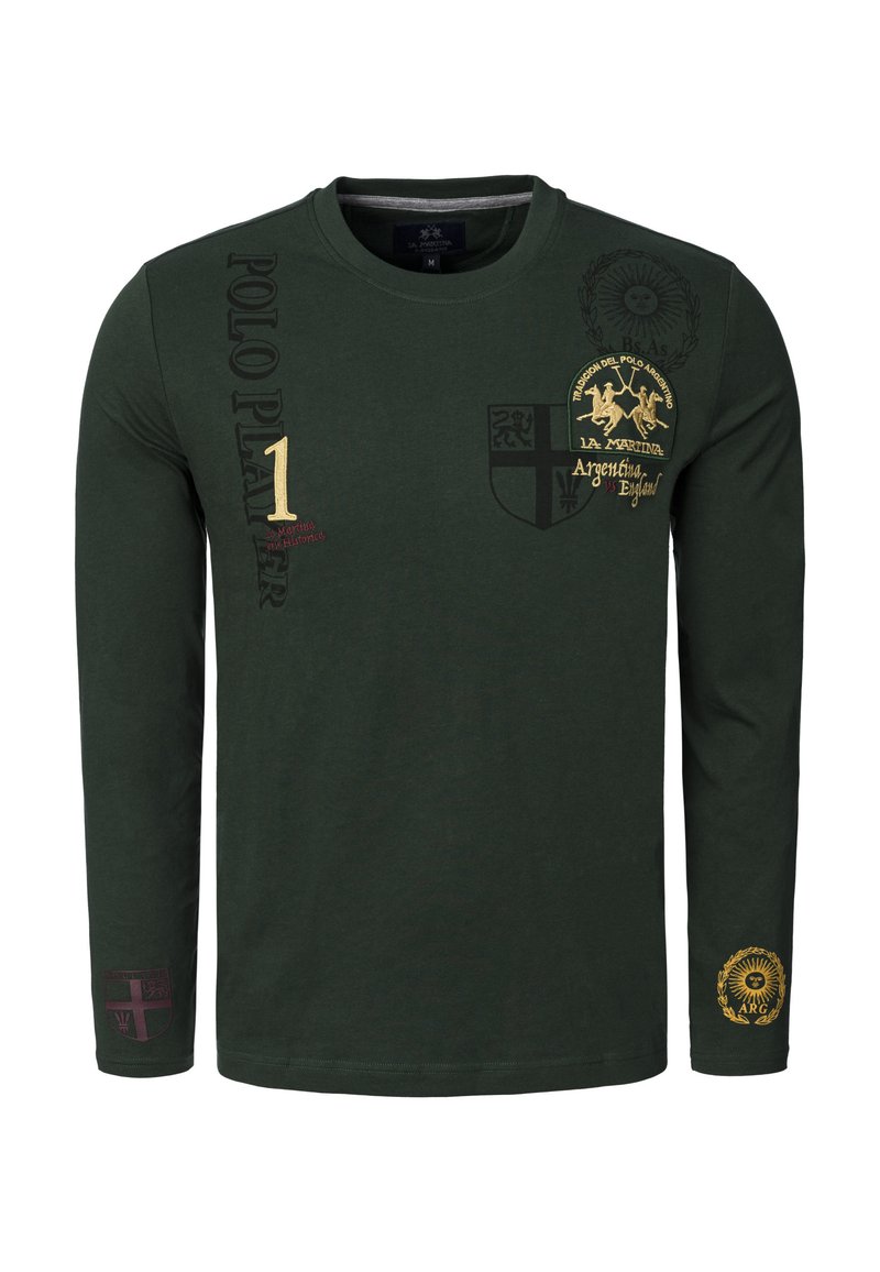 Bavlněná košile s dlouhým rukávem v tmavě zelené barvě, zdobená vyšívanými motivy a textem ve zlaté a vínové barvě. Výrazné erby a grafické akcenty jsou také součástí designu.