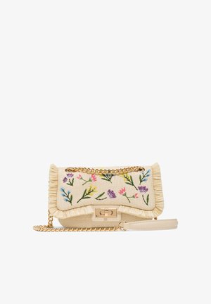Beige strukturierte Handtasche mit mehrfarbiger Blumenstickerei, Fransenbesatz, goldener Kettenriemen und rechteckigem goldfarbenem Verschluss auf weißem Hintergrund.