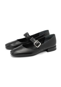 Zapatos de cuero negros con punta cuadrada, una sola correa con una hebilla decorativa y un tacón bajo tipo bloque. Textura suave, diseño minimalista.