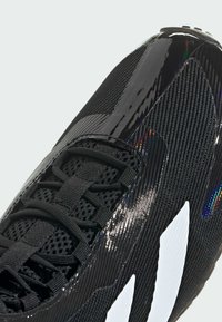 Black athletic shoe featuring a textured fabric upper with glossy accents, intricate lacing system, and prominent white logo detail.