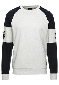 Sudadera gris claro con mangas raglán en azul marino, cuello redondo, puños y dobladillo acanalados. Presenta un detalle de logo en la manga izquierda. Textura de tela suave.