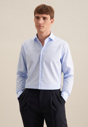 Hellblaues Hemd mit Knopfleiste, aus glattem Stoff, mit langen Ärmeln und spitzem Kragen, kombiniert mit dunklen Hosen. Schlichtes Design, keine Muster.