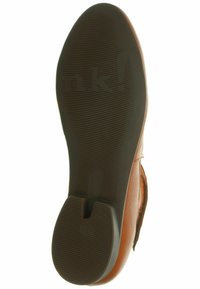 Suola di scarpa marrone con un design flessibile e scanalature testurizzate per una migliore aderenza, contrassegnata con il nome del marchio "nk!" in caratteri in grassetto.