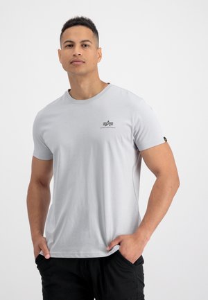 Svijetlo sivi kratki rukav T-shirt od pamuka, s malim crnim logotipom na prsima i oznakom na rukavu. Glatka tekstura.