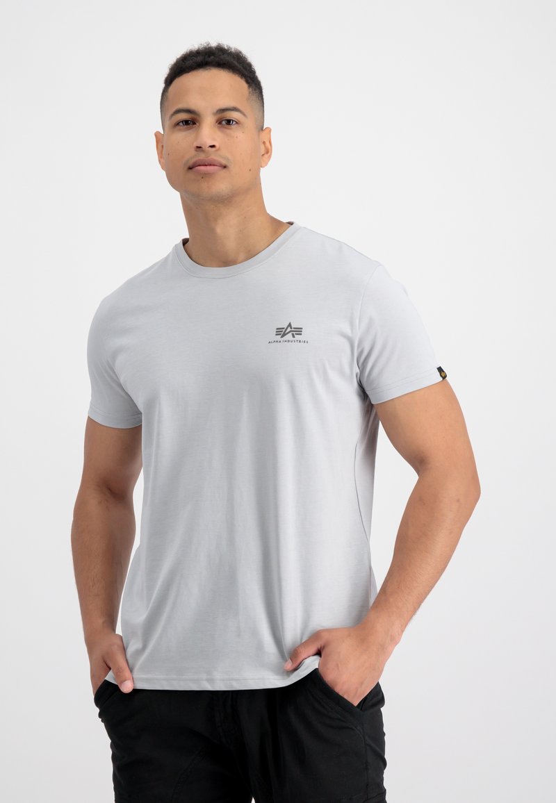 Világosszürke, rövid ujjú póló, pamutból készült, kicsi fekete logóval a mellrészen és címkével a hajtókán. Sima textúrájú.