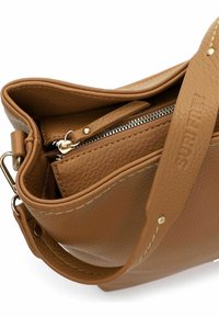 Bolso de mano de cuero marrón con superficie texturizada, cierre de cremallera y una correa desmontable. Presenta herrajes en tono dorado y detalles cosidos.