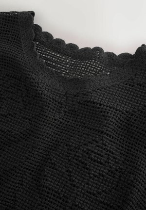 Černá háčkovaná látka s otevřenou vazbou a vroubkovaným okrajem, s texturovanými vzory po celé ploše a měkkou, pružnou strukturou.