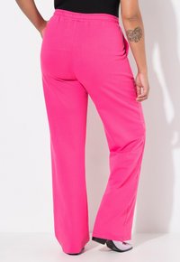 Pantalons extensibles roses avec une taille élastique, présentant une coupe décontractée et des jambes droites, fabriqués à partir d'un tissu doux. Design simple, sans motifs ni accents.