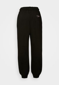 Svarta joggers med elastisk midja, samlade muddarna och en liten broderad logga i rosa på framsidan. Tillverkade av mjukt tyg.