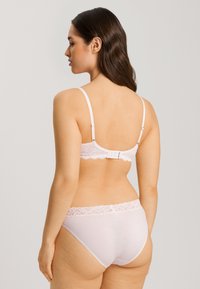 Roze kanten beha en bijpassende slip tonen een gestructureerde kanten band, verstelbare bandjes en een haak-en-oogsluiting op de rug.