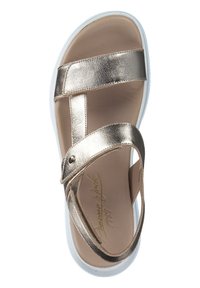 Metallisk guldslip-in med två breda remmar, vit sula och ljust beige innersula. Har en metalldekor vid ankeln.