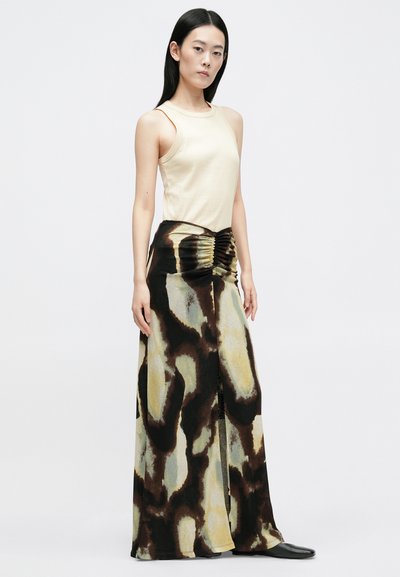 Top in tessuto beige abbinato a una lunga gonna stampata con tonalità astratte di marrone e giallo, con dettagli arricciati in vita.