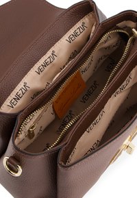 Braunes, strukturiertes Lederhandtascheninnenteil mit zwei Reißverschlussfächern, beiger Futter mit wiederholtem "Venezia"-Muster, goldfarbene Beschläge.