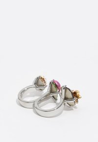 Dos anillos con bandas de plata, cada uno adornado con piedras preciosas triángulares de varios colores: acentos en rosa, verde y amarillo.