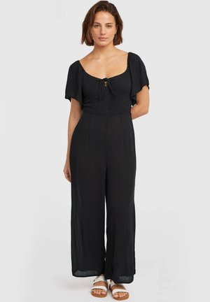 Combinaison noire avec manches courtes volantées, encolure carrée, détail noué à l'avant, pantalon à jambes larges, confectionnée dans un tissu léger.