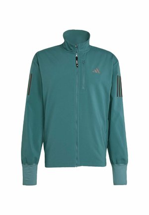 Veste de sport en teal fabriquée dans un matériau lisse et léger. Dotée d'un col haut, d'une fermeture éclair à l'avant et de trois bandes sombres sur les épaules.