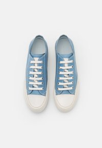 Zapatillas de cuero azul con suelas de goma blanca, punteras redondas y cordones blancos. Presentan costuras decorativas a lo largo de los bordes y una textura suave.