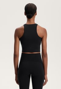 Top corto nero con design a corsetto, realizzato in un materiale morbido e elasticizzato. Cuciture decorative sul retro e logo sul collo.