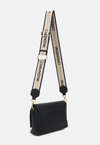 Czarna skórzana torebka na ramię o sztywnej formie, z przednią kieszenią i odpinanym paskiem w beżowo-czarny wzór z logo.