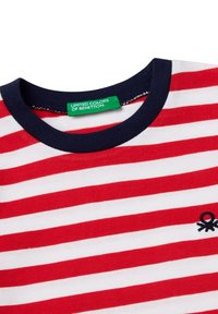 Rot-weißer gestreifter T-Shirt mit einem marineblauen Rundhalsausschnitt. Hat ein kleines schwarzes Logo-Design unten links. Hergestellt aus Baumwolle.