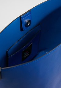 Borsa a mano in pelle blu con texture liscia, dotata di chiusura a scatto e tasca interna. Foderata con un tessuto blu abbinate.