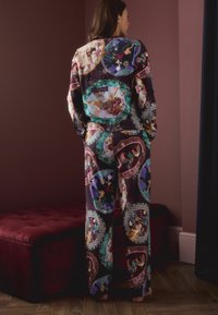 Bunt gemustertes Pyjama-Set mit einem dekorativen Oberteil und einer dazu passenden Hose, hergestellt aus weichem Stoff mit runden Designelementen und abwechslungsreichen Illustrationen.