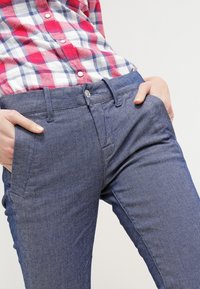 Mörkbla denimbyxor med skräddarsydd passform, som har framfickor och bältesömmar. Tyget har en lätt stretch och en slät textur.