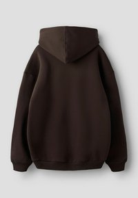 Smeđa majica s kapuljačom s velikim džepom na leđima, kapuljačom sa špagom i rebrastim rubovima na donjem dijelu. Mekani materijal glatke teksture.