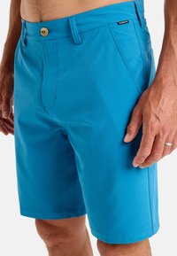 Blue shorts made of lightweight fabric, featuring a button closure, side pockets, and a smooth texture with clean stitching details.