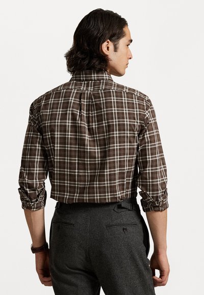 Brun rutete skjorte med knapp-der-u collar, rullede ermer og en folder detalj bak, kombinert med mørkegrå bukser.